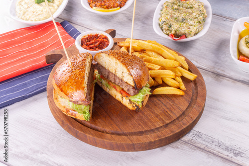 Big sandwich - hamburger with juicy beef burger cheese tomato and red onion on wooden background