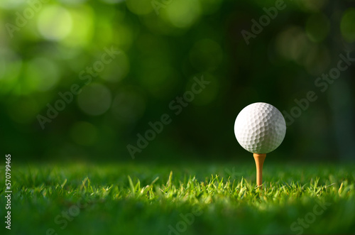 Fotografia Close-up golf ball on tee with blur green bokeh background.