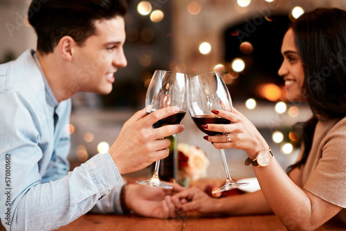 Couple holding hands at table, love and cheers with wine on valentines day date at home with smile and bokeh. Date night, man and woman in living room, valentine celebration and happy relationship.