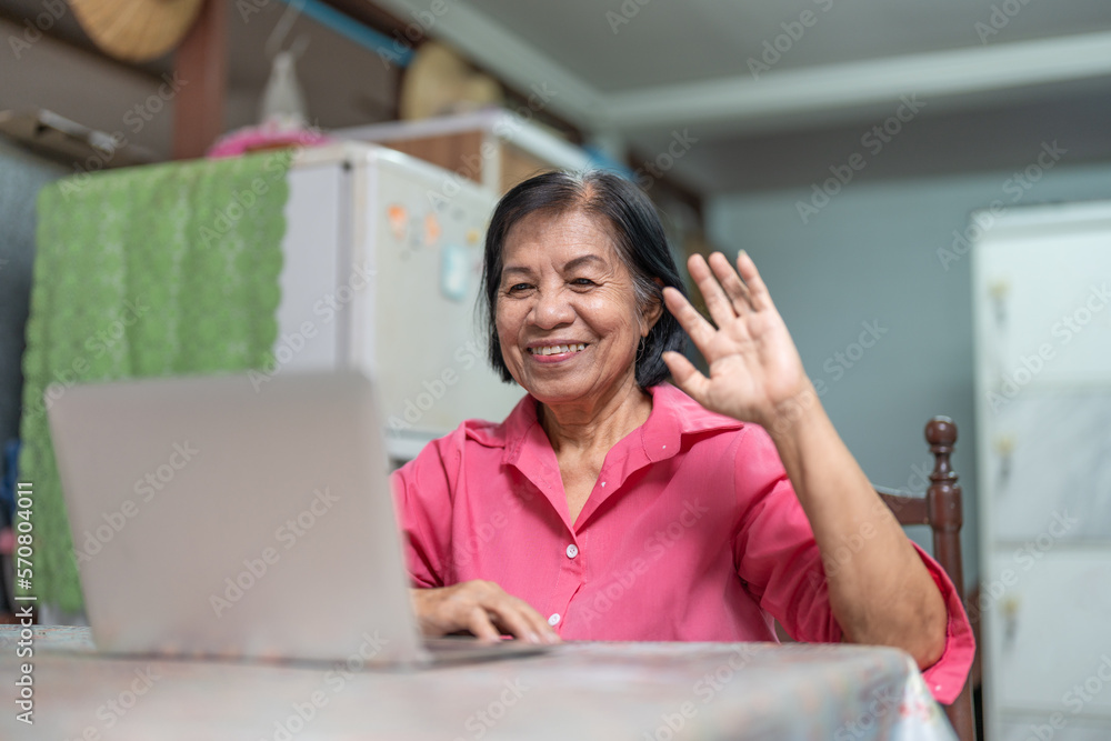 Happy Asian elderly woman using laptop talking with family in video conference online Happy Asian elderly woman using laptop talking with family in video conference online