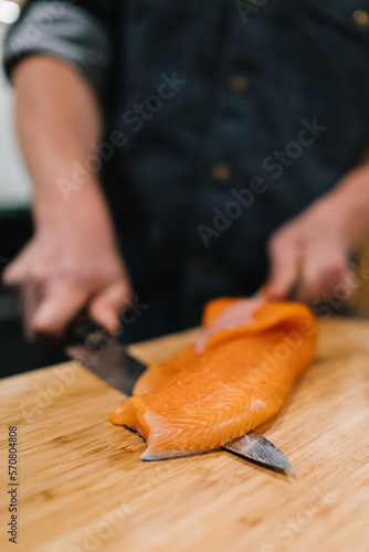 Ein Stück Fisch wird von einem Koch filetiert (ID: 570804808)