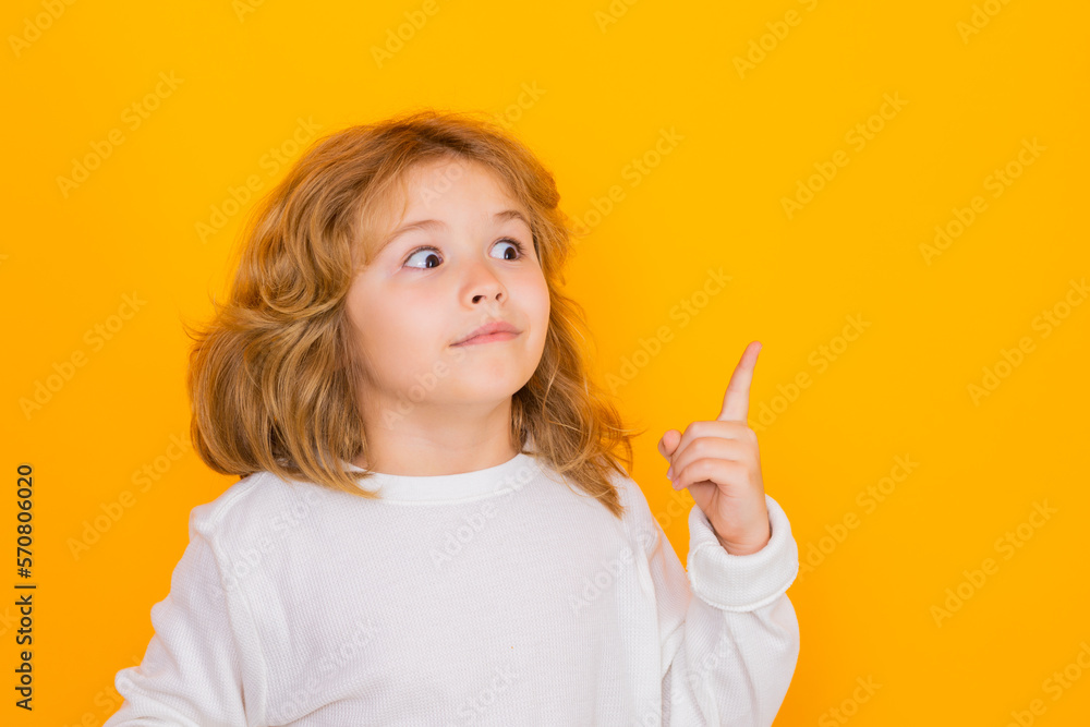 Child pointing up on yellow isolated studio background. Shocked kid pointing to copyspace, showing promo offers, points up. Child pointing up on yellow isolated studio background. Shocked kid pointing to copyspace, showing promo offers, points up.