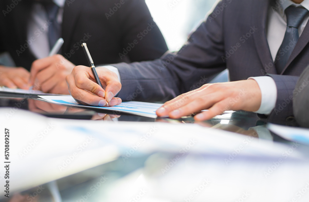Business professionals working together at office desk, analyzing financial statistics displayed on the laptop screen. Business professionals working together at office desk, analyzing financial statistics displayed on the laptop screen.