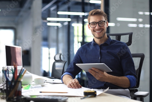 Young modern business man working using digital tablet while sitting in the office.