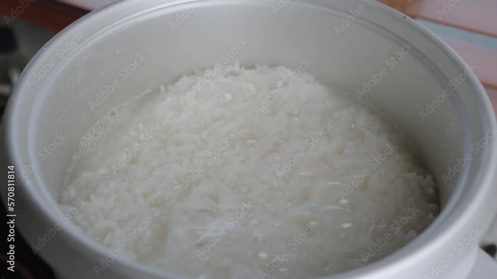 White Thai jasmine rice boiled in a rice cooker bowl close up. Rice is the most important food crop with regard to human nutrition and caloric intake. White Thai jasmine rice boiled in a rice cooker bowl close up. Rice is the most important food crop with regard to human nutrition and caloric intake.