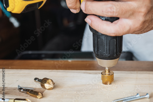 Carpenter use countersink bit to drill both a pilot hole and use countersink bit to recess the head of the screw into wood plank. DIY maker and woodworking concept. selective focus