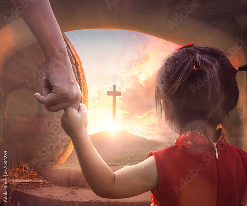 Foto Easter concept: Child's hand holding mother's finger on blurred The cross of jesus christ background
