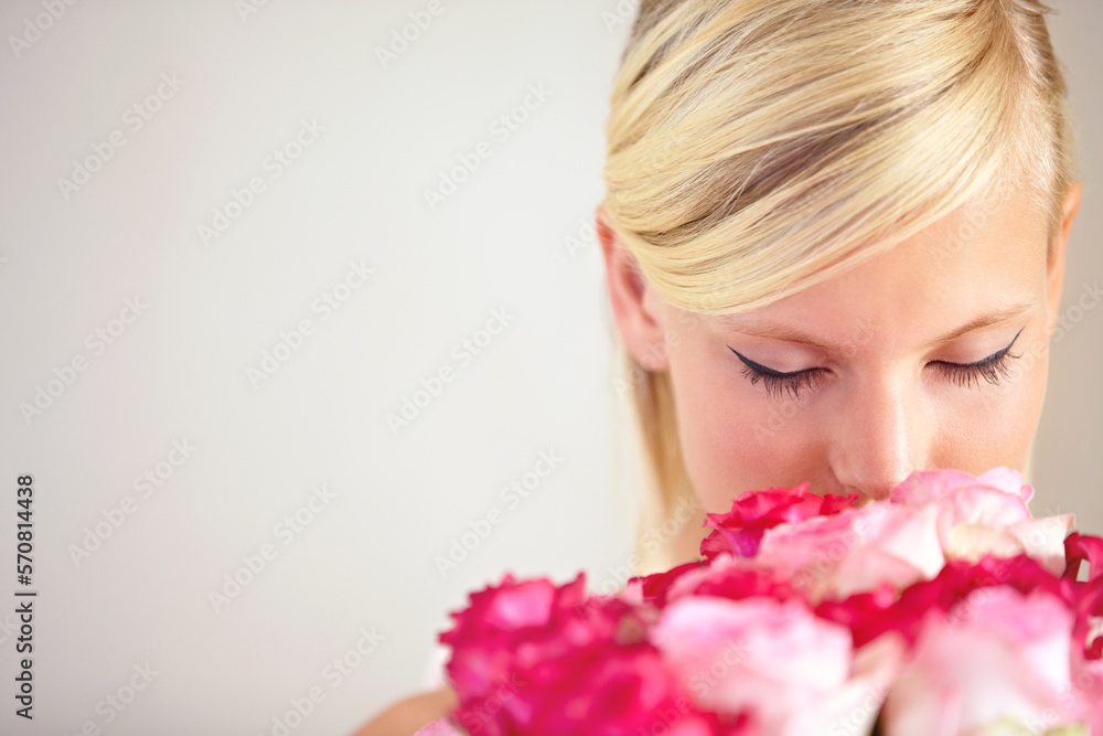 Fototapeta premium Smelling, floral and woman with flowers as a gift isolated on a grey studio background. Surprise, romantic and girl with a bouquet of roses for valentines day on a backdrop with mockup space