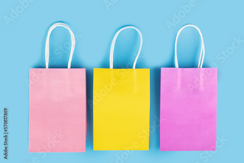 gift bag, bright multicolored shopping bags on a blue background, space for text, online shopping, top view