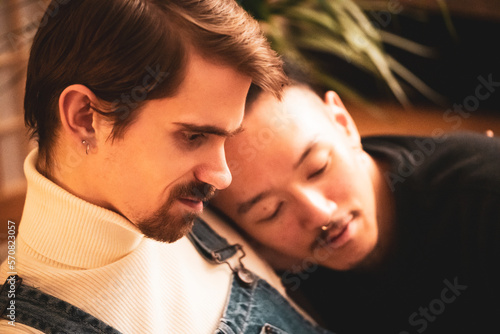 Gay male inter-racial couple cuddle and smile during virus lock down photo