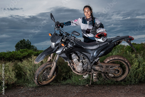 Woman posing behind her super moto style motorcycle on dirt road photo