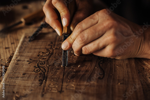 Close up process of decorative wood engraving using hand tools photo