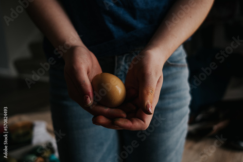 front view of older girl holding a yellow dyed chicken egg photo