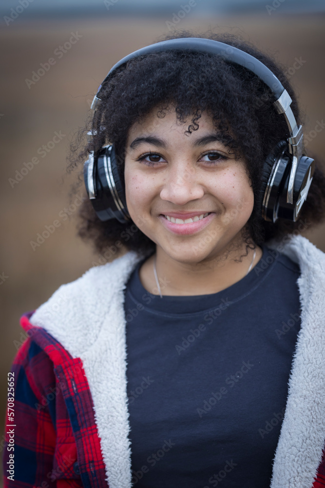 biracial teen girl wearing headphones and smiling biracial teen girl wearing headphones and smiling