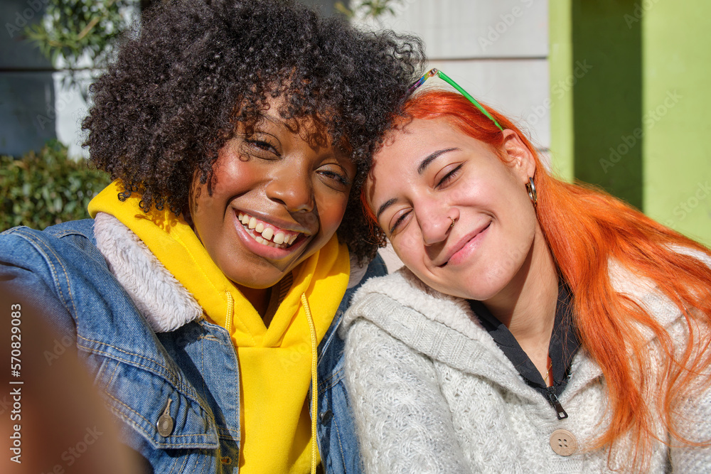 two young friends smiling taking a selfie one black afro hair and the other white orange hair two young friends smiling taking a selfie one black afro hair and the other white orange hair