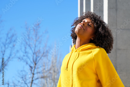 young black girl with afro hair with eyes closed breathing deeply facing the sun
