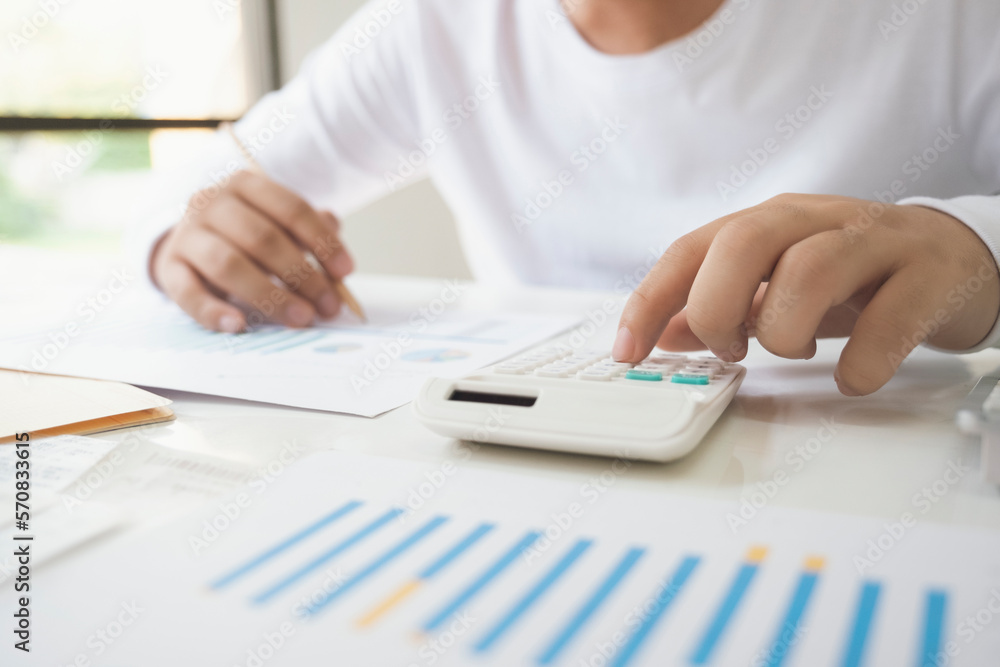 Business man Using calculator analyzing investment chart on the 