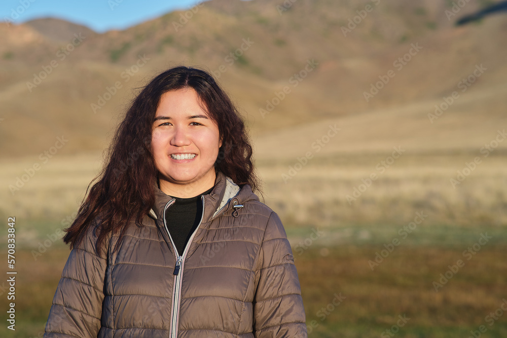 Portrait of an Asian smiling woman standing against the hills