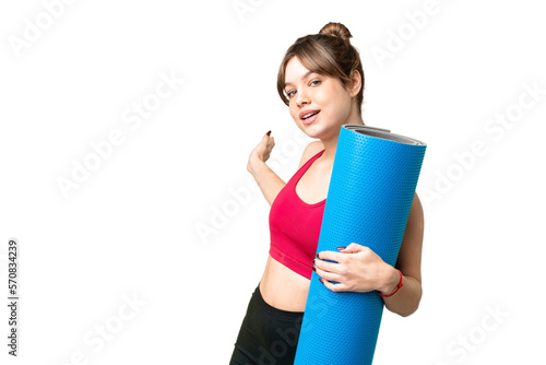 Young sport girl going to yoga classes while holding a mat over isolated chroma key background extending hands to the side for inviting to come