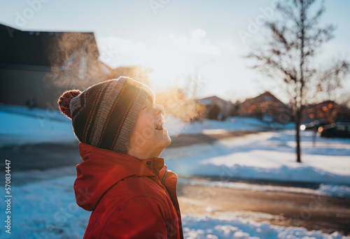 Boy in winter clothing laughing in frosty air on sunny winter day. photo