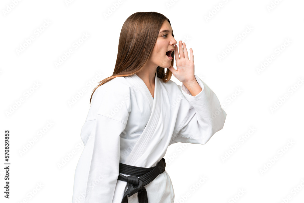 Teenager girl doing karate over isolated chroma key background shouting with mouth wide open to the side Teenager girl doing karate over isolated chroma key background shouting with mouth wide open to the side