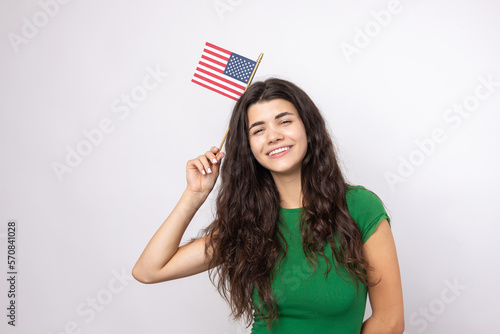 A young happy girl with a smile on her face holds an American flag in her hands. Symbol of patriotism and freedom.
