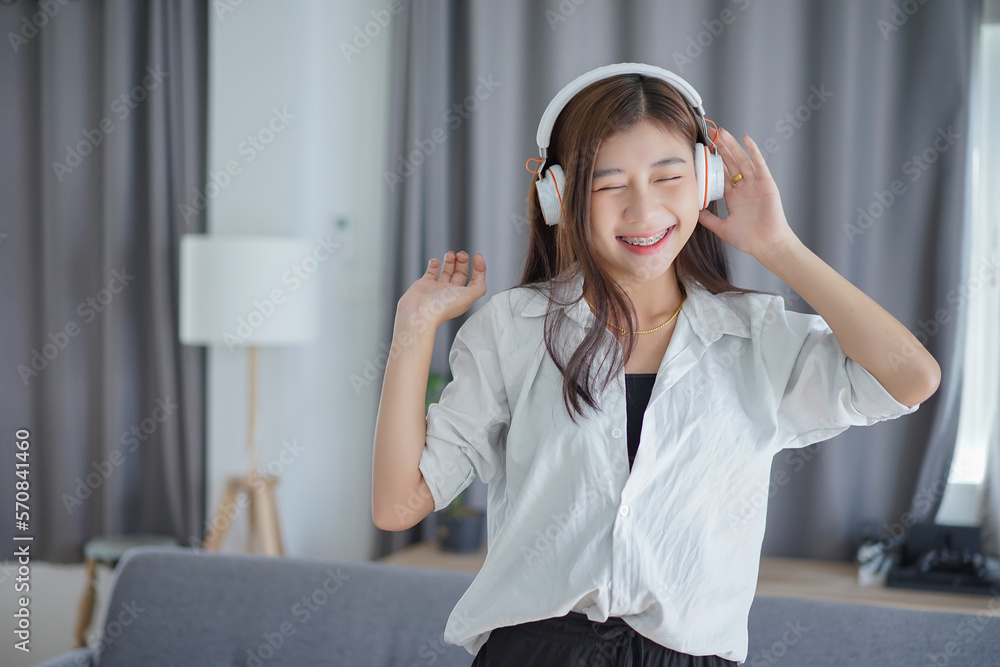 Happy asian carefree young woman dancing alone having fun at home listening to good music. Happy asian carefree young woman dancing alone having fun at home listening to good music.