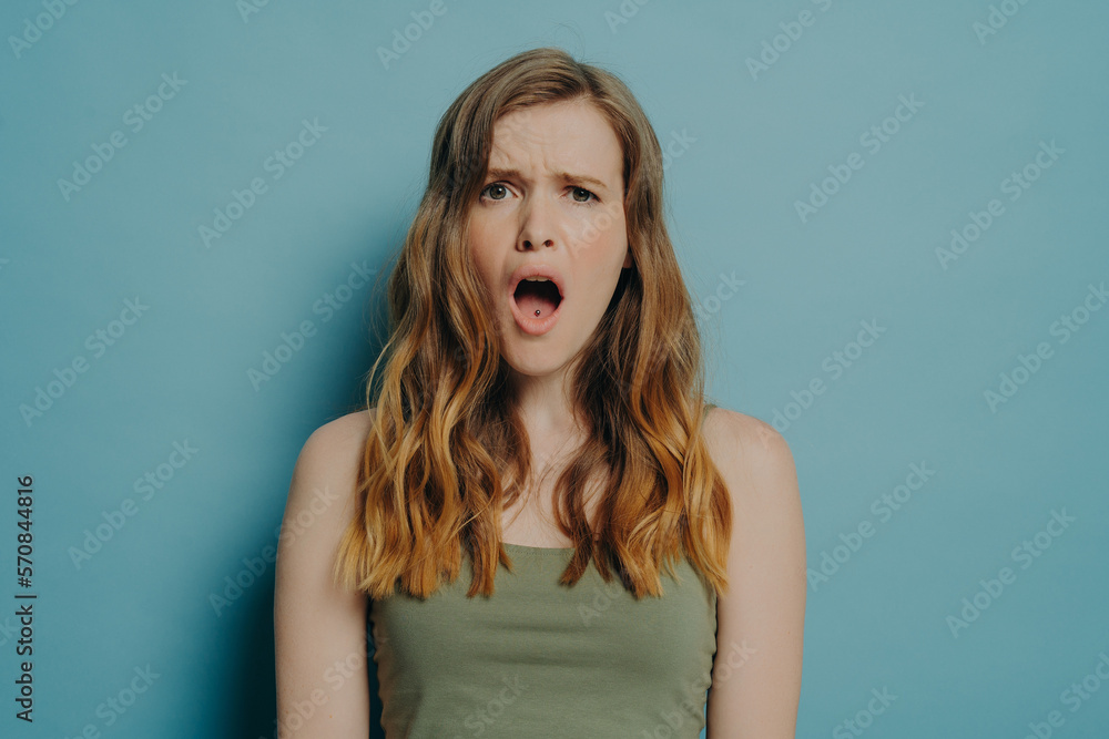 Young displeased woman with dissatisfied face expression and open mouth seeing something ugly Young displeased woman with dissatisfied face expression and open mouth seeing something ugly