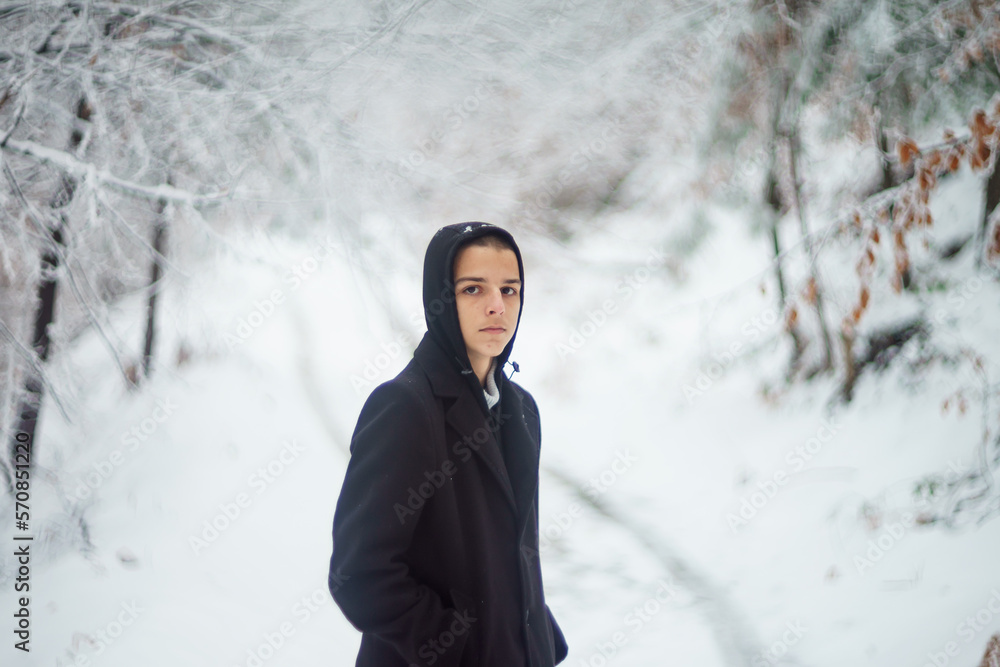 handsome young man is standing on a road covered with snow handsome young man is standing on a road covered with snow