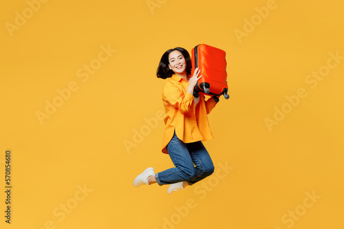 Side view young woman in summer casual clothes jump high hold hug suitcase isolated on plain yellow background. Tourist travel abroad in free spare time rest getaway. Air flight trip journey concept #570854680