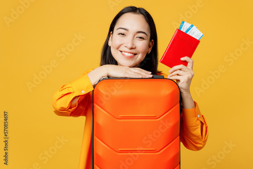 Young cheerful woman wear summer casual clothes hold passport ticket valise isolated on plain yellow background. Tourist travel abroad in free spare time rest getaway. Air flight trip journey concept. #570854697