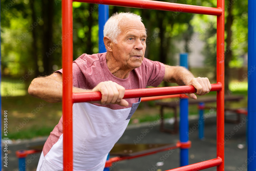 Obraz premium Sportive elderly man training on outdoor sports ground