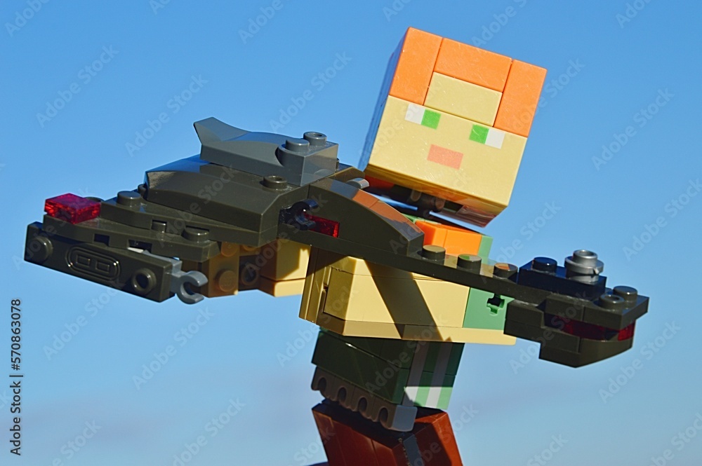 Naklejka premium LEGO Minecraft large figure of female character Alex holding model of Klingon battleship Bird Of Prey from TV and movie series Star Trek, made by KREO. Blue winter skies in background.