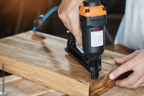 Obraz na płótnie carpenter using nail gun or brad nailer tool on wood box in a workshop ,furniture restoration woodworking concept. selective focus w salonie