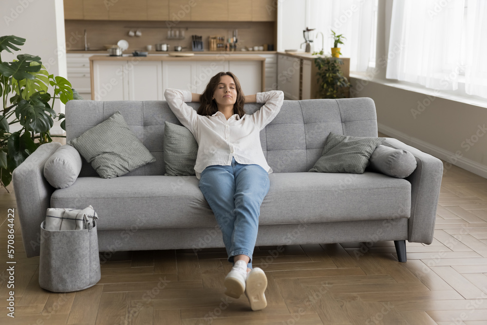 Relaxed sleepy young woman sitting on sofa, leaning on back, stretching body, resting on comfortable couch, breathing fresh air, sleeping on break, enjoying calm silent leisure time Relaxed sleepy young woman sitting on sofa, leaning on back, stretching body, resting on comfortable couch, breathing fresh air, sleeping on break, enjoying calm silent leisure time