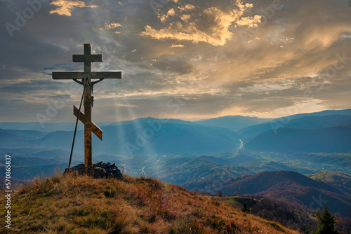 Christian cross on the mountain top at the sunset.