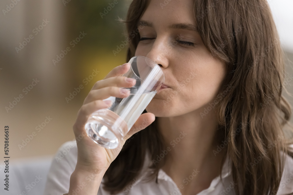 Thirsty young woman drinking clear natural cold water with closed eyes, holding transparent glass, keeping healthy hydration balance, taking care of nutrition, diet. Close up shot Thirsty young woman drinking clear natural cold water with closed eyes, holding transparent glass, keeping healthy hydration balance, taking care of nutrition, diet. Close up shot