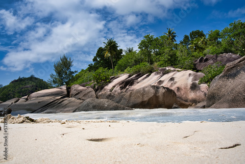 Low angle shot of beach, rock boulders and lush vegetation 