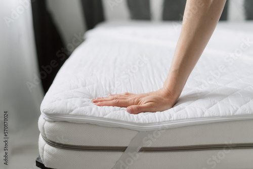 woman check mattress with textile cover in bedroom, closeup photo