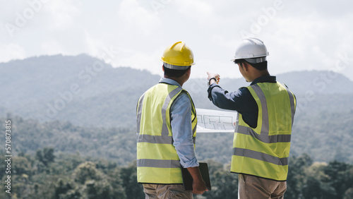 Two young maintenance engineer man working with blueprint on the mountain, Environmental engineering concept..
