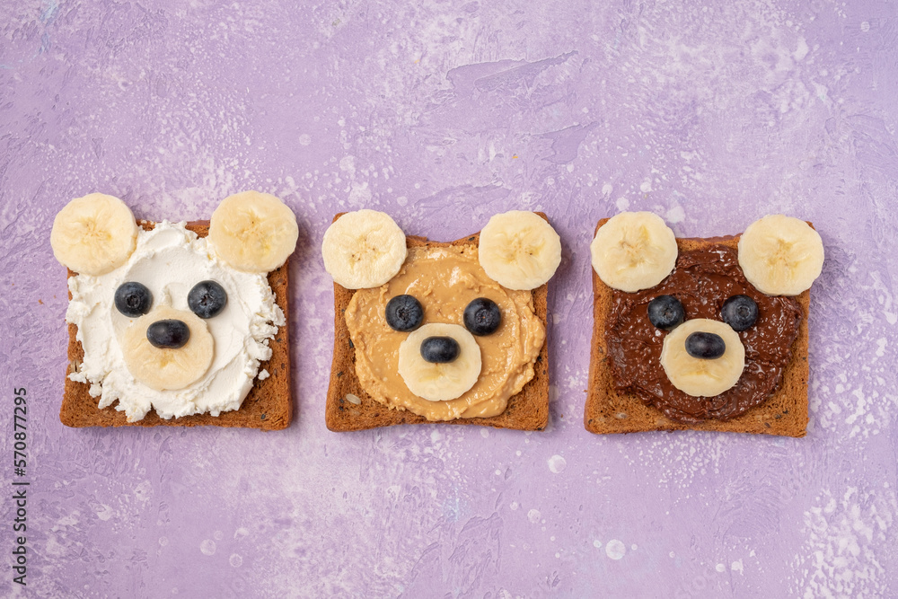 Breakfast toasts with nut butter, banana and blueberry with cute funny animal face. Kids food, breakfast for kids or school lunch. Top view Breakfast toasts with nut butter, banana and blueberry with cute funny animal face. Kids food, breakfast for kids or school lunch. Top view