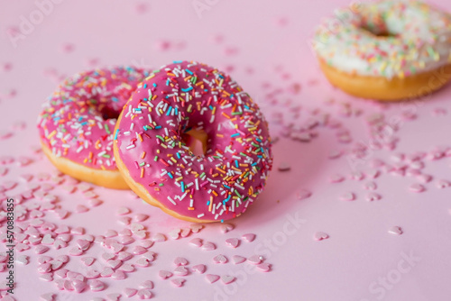 Delicious dessert. Pink donuts with multicolored sprinkles on a pink background of Sweets. Confectionery products.