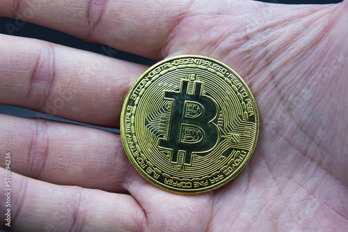 Finger hold bitcoin golden on black. Hand hold gold bitcoin crypto money concept. On a black background we look at a virtual currency, namely the cryptocurrency bitcoin, held in the right mine.