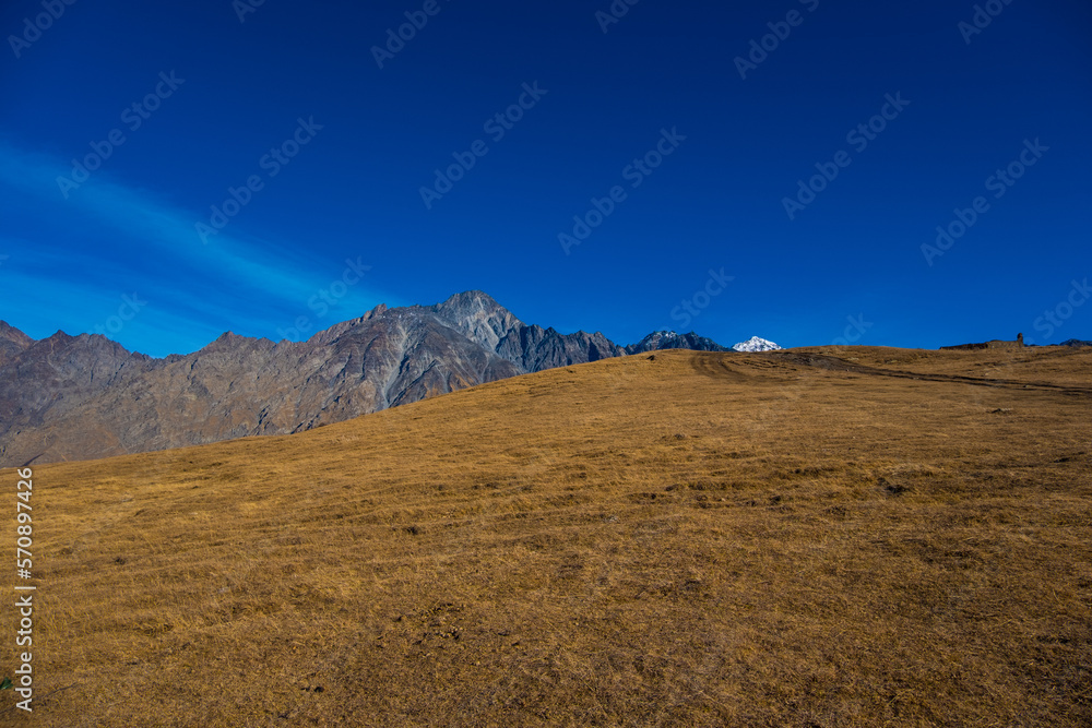 Fototapeta premium Georgia : 10-11-2022 : Country of Georgia, Kazbegi, Panoramic landscape of beautiful natural mountains, view of amazing Caucasus mountain peaks and meadows in Kazbegi national park