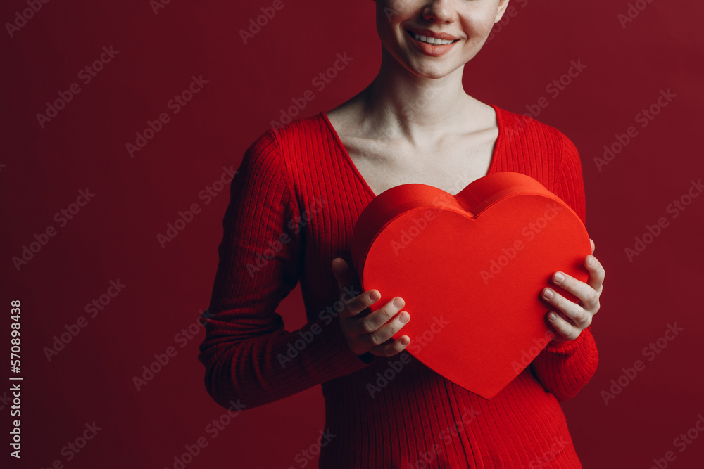 Happy young woman holding heart shaped box in Valentines day at red background. Happy young woman holding heart shaped box in Valentines day at red background.