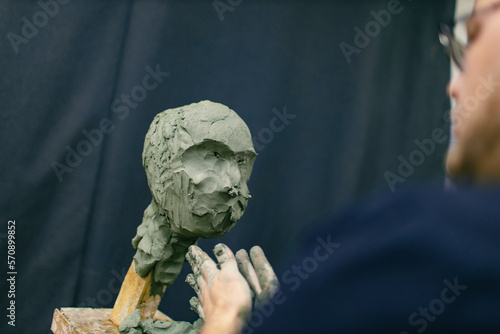 Man sculptor creates sculpt bust clay human woman sculpture. Statue craft creation workshop.