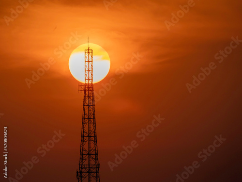 Sihouette of telecommunication pole or satellite radio station tower with big sun background