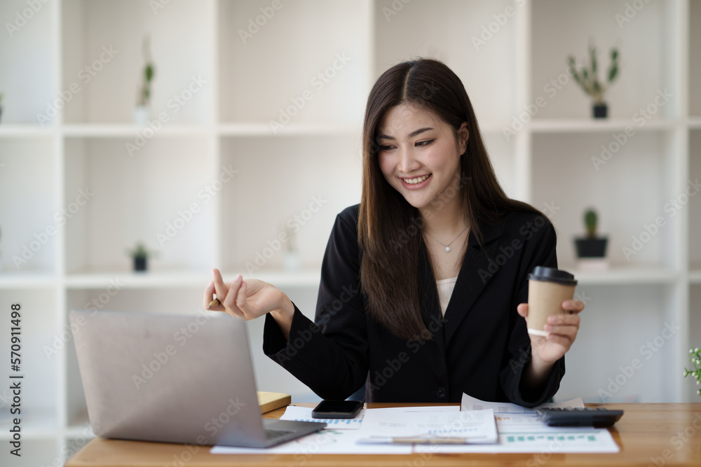 Happy Asian businesswoman working for her project and drinking coffee cup while working, sitting at the office desk. Happy Asian businesswoman working for her project and drinking coffee cup while working, sitting at the office desk.