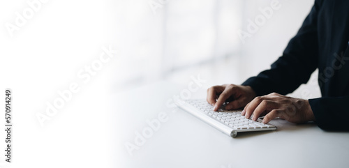 Close up view of young businessman typing on keyboard while working in the bright modern office room.