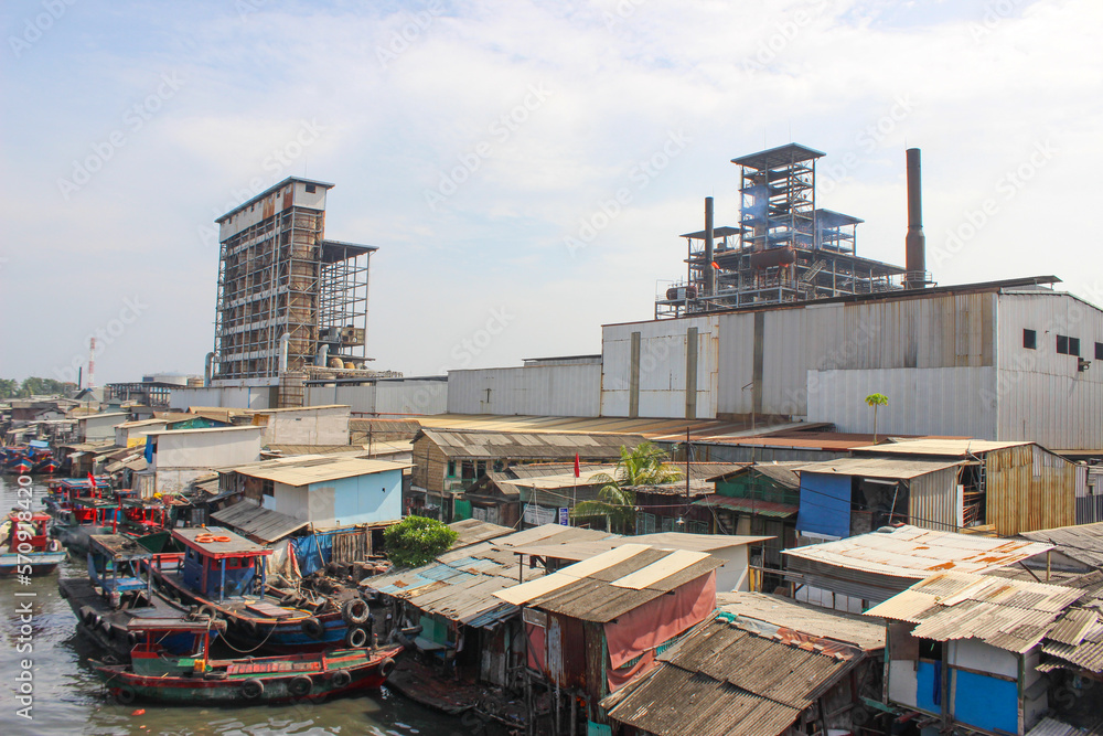 Fototapeta premium portrait of t fishing village beside industrial factory